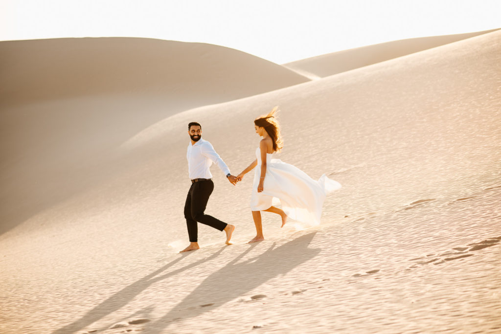 Sand dunes engagement couple running